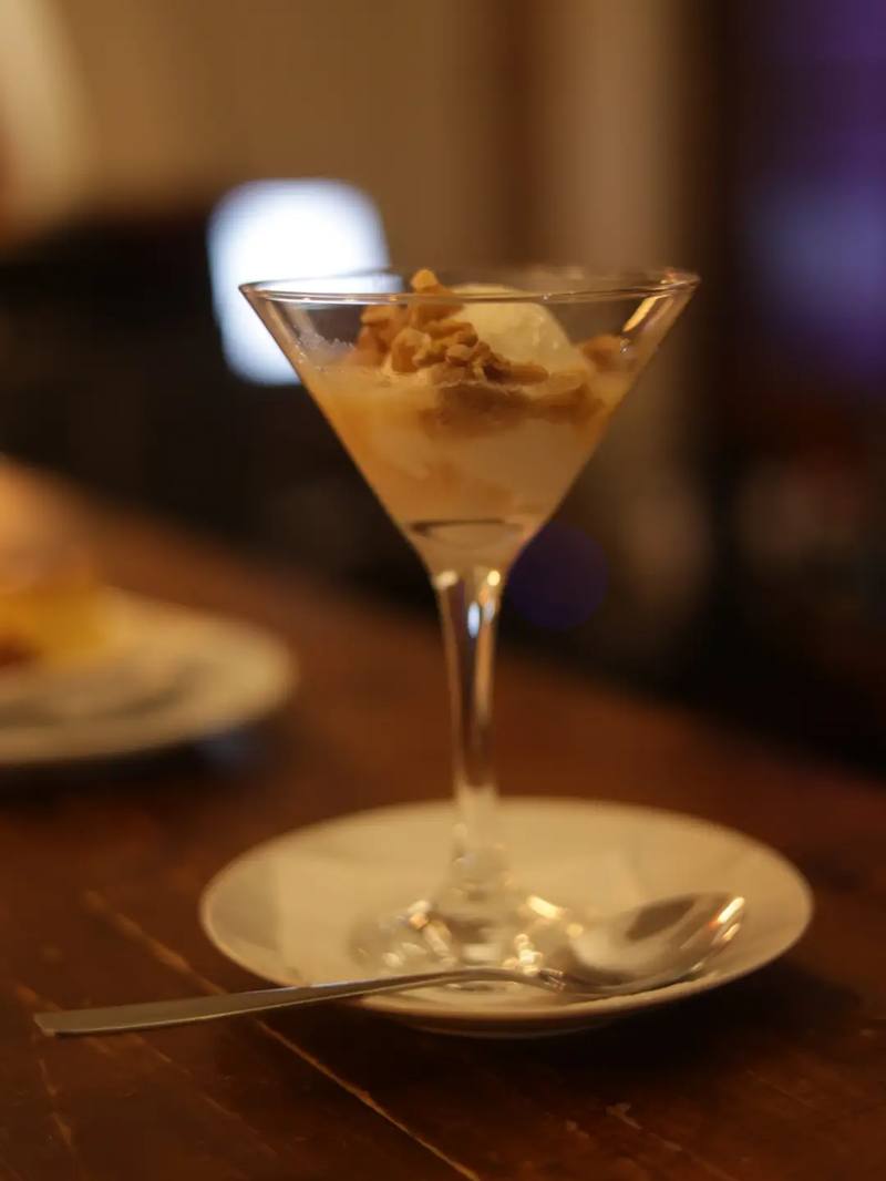 Postre servido en copa de cristal, con cuchara al costado